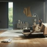 Saugroboter fährt durch ein helles, modernes Wohnzimmer mit Holzboden